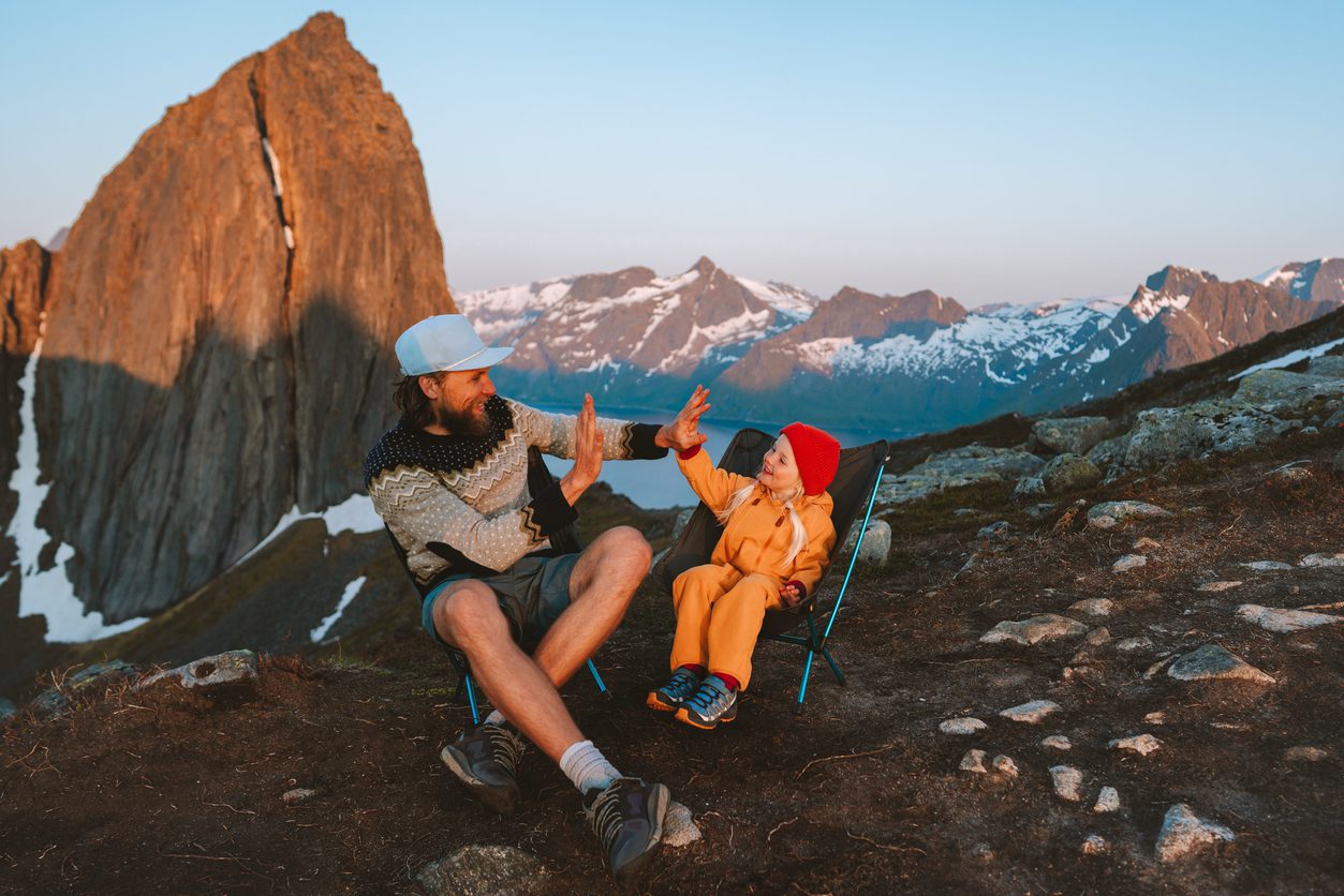 Family time father and child daughter playing high five hands traveling in Norway mountains dad with daughter hiking together sitting in camping chairs adventure vacations lifestyle outdoor